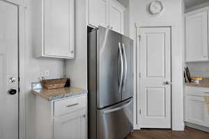 Kitchen featuring dark wood-style flooring, freestanding refrigerator, and white cabinets