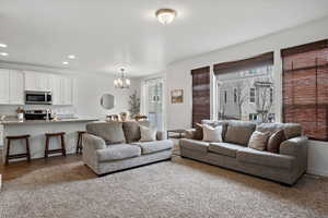 Living area with a wealth of natural light, wood finished floors, a notable chandelier, and recessed lighting