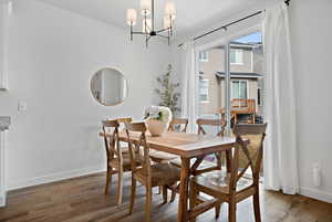 Dining area featuring a notable chandelier, baseboards, and wood finished floors
