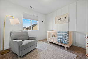 Carpeted bedroom with a nursery area, baseboards, and visible vents