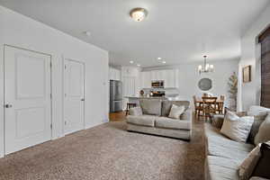 Living room featuring light carpet, visible vents, a notable chandelier, and recessed lighting