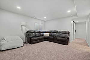Carpeted living room with baseboards, a textured ceiling, visible vents, and recessed lighting