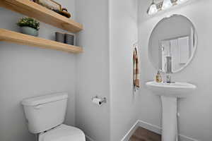 Bathroom featuring baseboards, a sink, toilet, and wood finished floors
