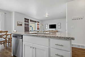 Kitchen featuring dark wood finished floors, visible vents, open floor plan, a sink, and dishwasher