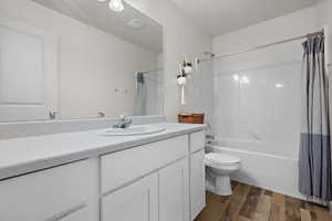 Bathroom featuring shower / bath combination with curtain, visible vents, toilet, vanity, and wood finished floors