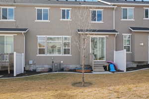 Back of house with central air condition unit, a yard, and stucco siding