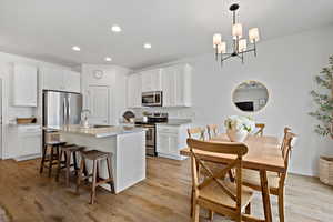 Kitchen with white cabinets, light wood finished floors, stainless steel appliances, and a sink