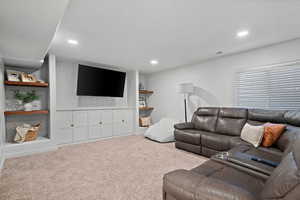 Carpeted living area with visible vents and recessed lighting