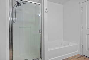 Bathroom featuring a stall shower, wood finished floors, and a bath