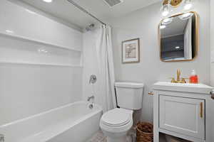 Bathroom featuring visible vents, shower / bathtub combination with curtain, toilet, vanity, and a textured ceiling