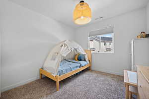Bedroom featuring carpet floors, visible vents, and baseboards