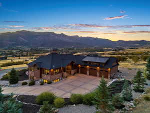 View of front of home featuring stone siding, a standing seam roof, concrete driveway, and a mountain view