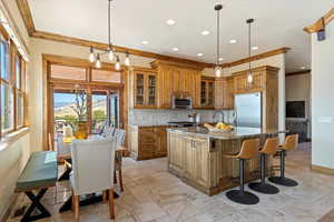 Kitchen featuring brown cabinetry, dark stone counters, a kitchen island with sink, stainless steel appliances, and backsplash