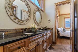 Bathroom with double vanity, connected bathroom, a sink, and a textured wall