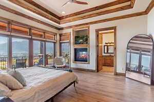 Bedroom with access to exterior, a multi sided fireplace, a mountain view, and crown molding