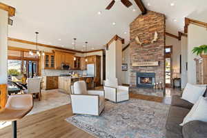 Living room with beam ceiling, a fireplace, light wood-style flooring, a ceiling fan, and high vaulted ceiling