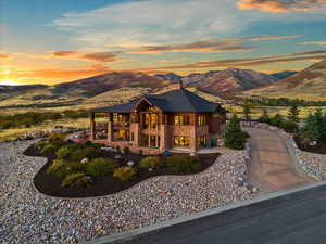 View of front of house featuring a mountain view, stone siding, a patio area, and a balcony