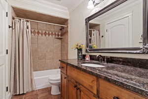 Bathroom featuring toilet, vanity, ornamental molding, tile patterned floors, and shower / tub combo with curtain