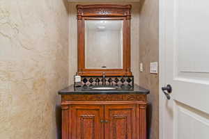 Bathroom featuring tasteful backsplash, a textured wall, and vanity