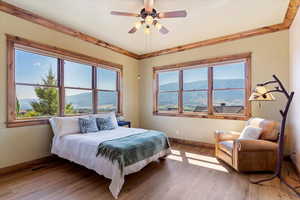 Bedroom with wood-type flooring, multiple windows, ornamental molding, and baseboards