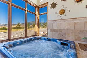 Sunroom featuring a hot tub and a mountain view