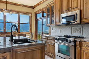 Kitchen featuring crown molding, decorative backsplash, stainless steel appliances, and a sink