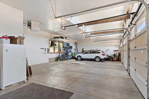 Garage featuring freestanding refrigerator and a garage door opener