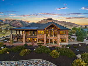 Rear view of house with a patio, metal roof, a mountain view, a balcony, and a chimney