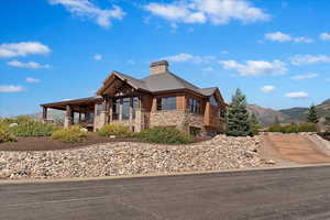 View of front facade featuring stone siding, a mountain view, and a chimney