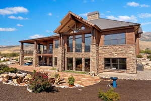 Rear view of property with stone siding, a patio area, a balcony, and central air condition unit