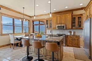 Kitchen featuring appliances with stainless steel finishes, stone tile flooring, brown cabinets, and ornamental molding