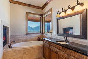 Full bathroom with vanity, ornamental molding, a tile fireplace, and a bath