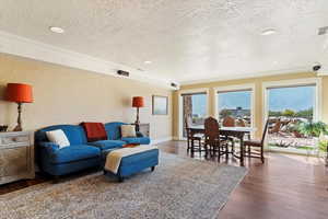 Living area with a textured ceiling, a textured wall, hardwood / wood-style floors, and baseboards