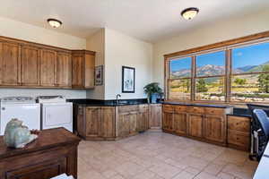 Kitchen featuring a textured ceiling, stone finish flooring, washing machine and dryer, and brown cabinets