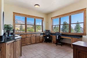 Office space featuring stone finish floor, a sink, built in desk, and a textured ceiling