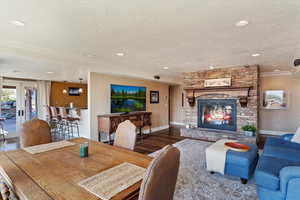 Living area with french doors, a fireplace, crown molding, a textured ceiling, and wood finished floors