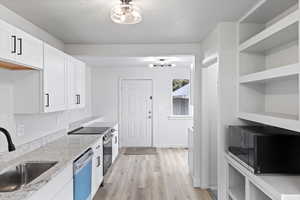 Kitchen featuring a sink, black microwave, open shelves, and dishwasher