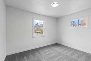 Carpeted spare room with a textured ceiling and baseboards