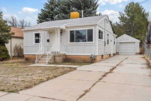 Bungalow-style house with an outbuilding, roof with shingles, a detached garage, concrete driveway, and board and batten siding