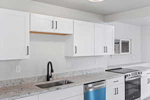 Kitchen with dishwashing machine, electric range, white cabinets, and a sink