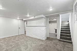 Finished below grade area featuring a bar, visible vents, stairway, and carpet flooring