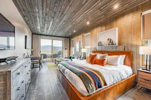 Bedroom with access to outside, wooden ceiling, a mountain view, and hardwood / wood-style flooring