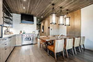 Kitchen with dark wood-style flooring, a sink, wood ceiling, designer range, and decorative backsplash