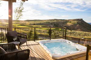 Deck featuring hot tub deck surround and a mountain view