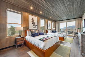 Bedroom with access to outside, wooden ceiling, wood walls, and hardwood / wood-style flooring