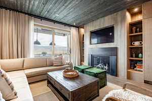 Living area with built in shelves, wood ceiling, and a large fireplace