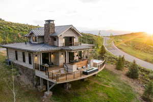 Back of house with a balcony, metal roof, a deck with mountain view, a standing seam roof, and central air condition unit