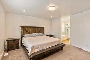 Bedroom with baseboards, visible vents, a textured ceiling, and light colored carpet