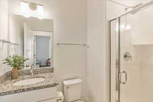 Bathroom featuring vanity, a shower stall, and toilet