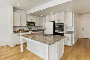 Kitchen featuring light wood-style flooring, stainless steel double oven, a sink, and freestanding refrigerator